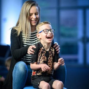 Boy siiting with his mum in a leopard skin design body splint laughing