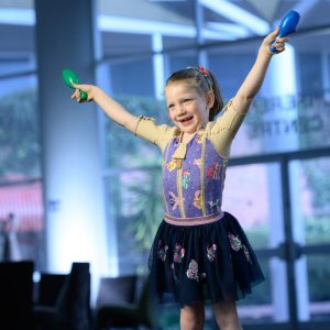 Girl in skirt and a body splint with unicorn design with her arms in the air